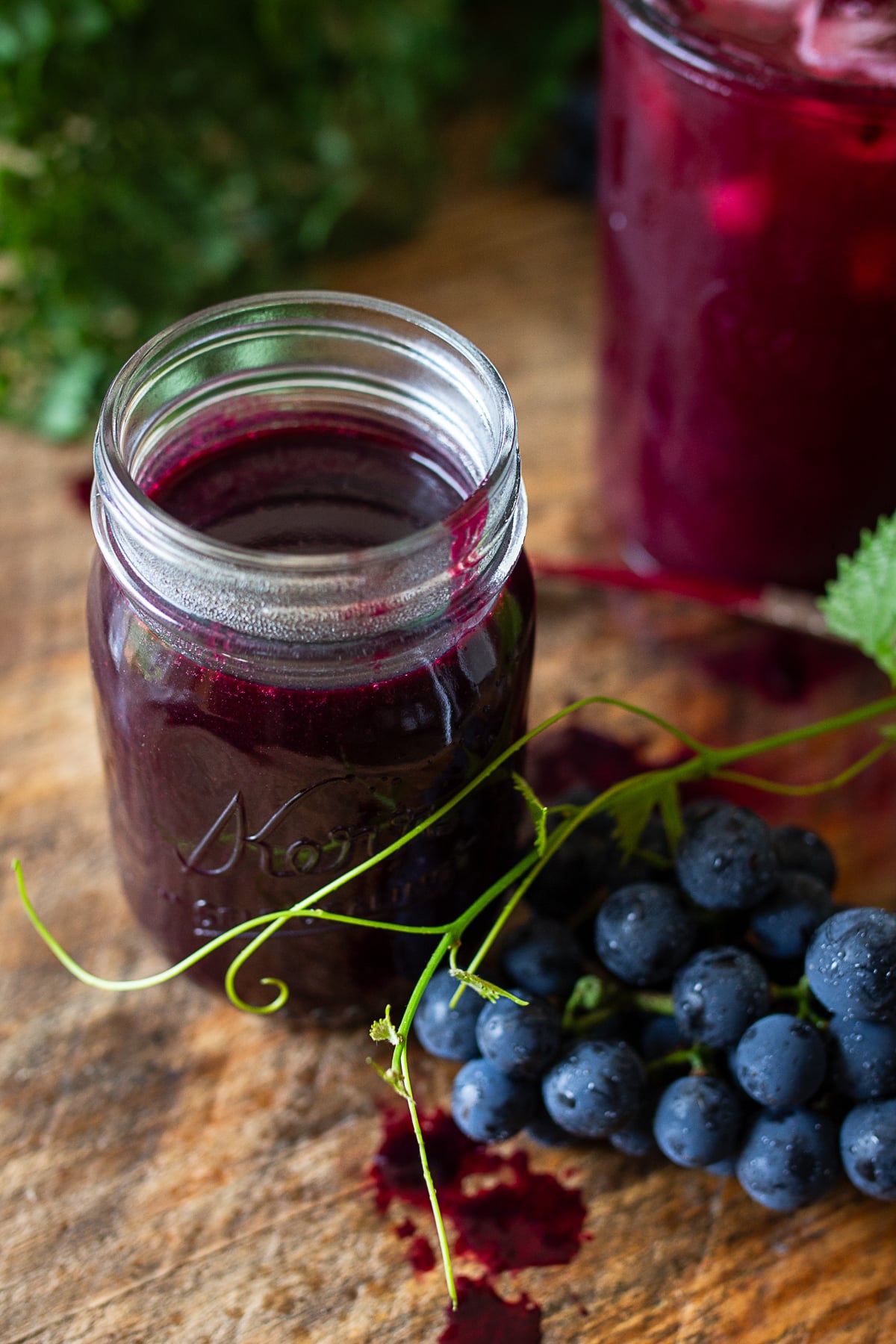 Homemade grape juice concentrate in a glass jar with fresh Concord grapes