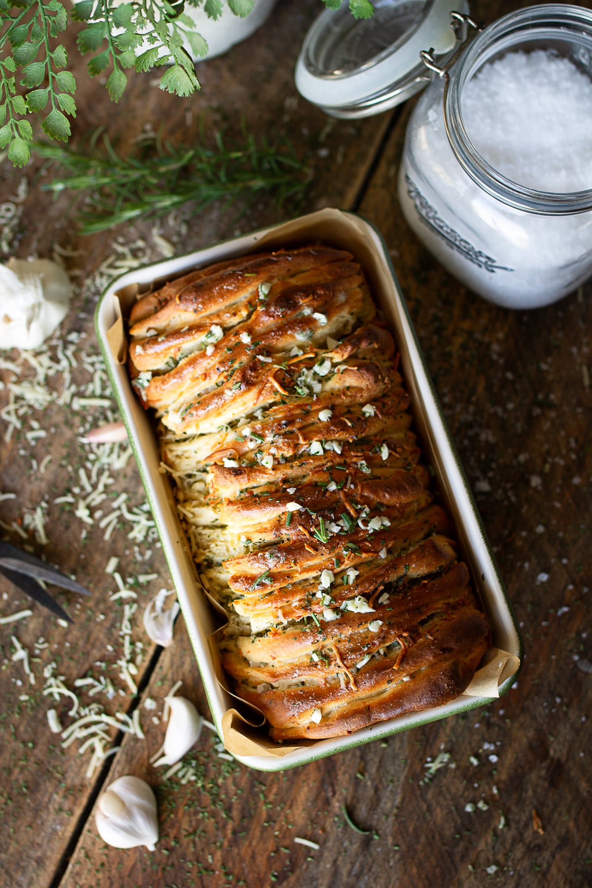 Golden brown rosemary garlic pull-apart bread fresh from the oven, topped with melted butter, minced garlic, and fresh herbs.