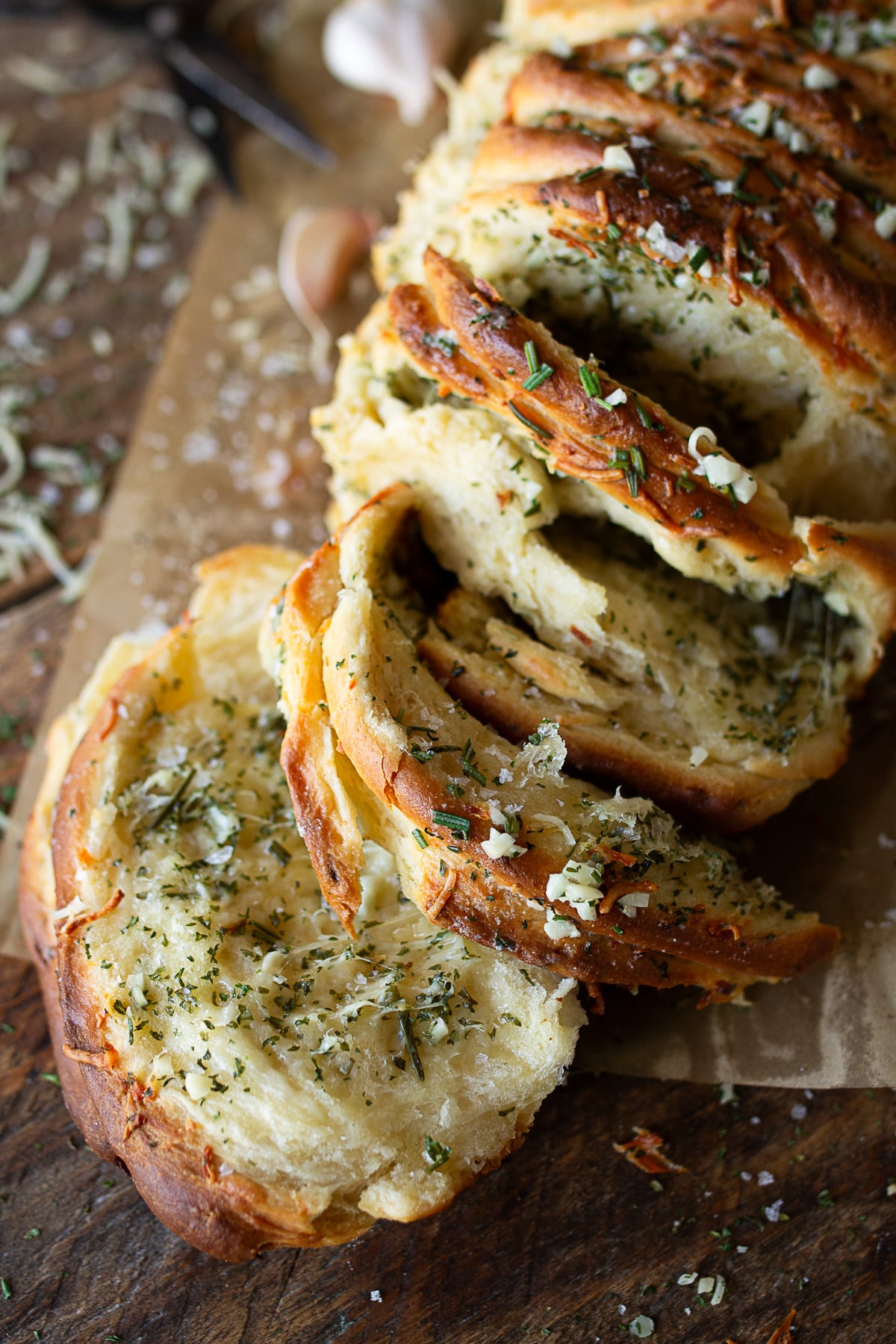 Soft, fluffy layers of homemade garlic pull-apart bread coated with melted herb butter, fresh rosemary, and parmesan cheese.