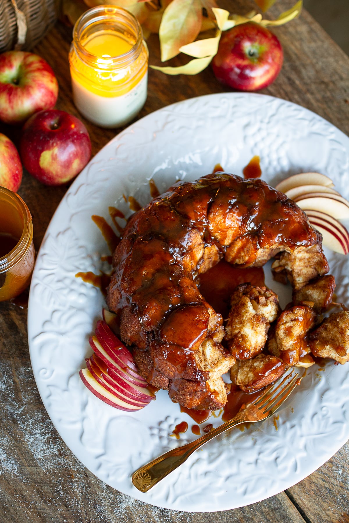 Close-up overhead view of pull-apart caramel apple monkey bread showing sticky cinnamon-sugar dough balls and sliced apples.