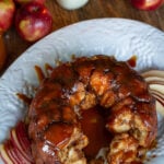 Close-up overhead view of pull-apart caramel apple monkey bread showing sticky cinnamon-sugar dough balls and sliced apples.