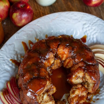 Close-up overhead view of pull-apart caramel apple monkey bread showing sticky cinnamon-sugar dough balls and sliced apples.