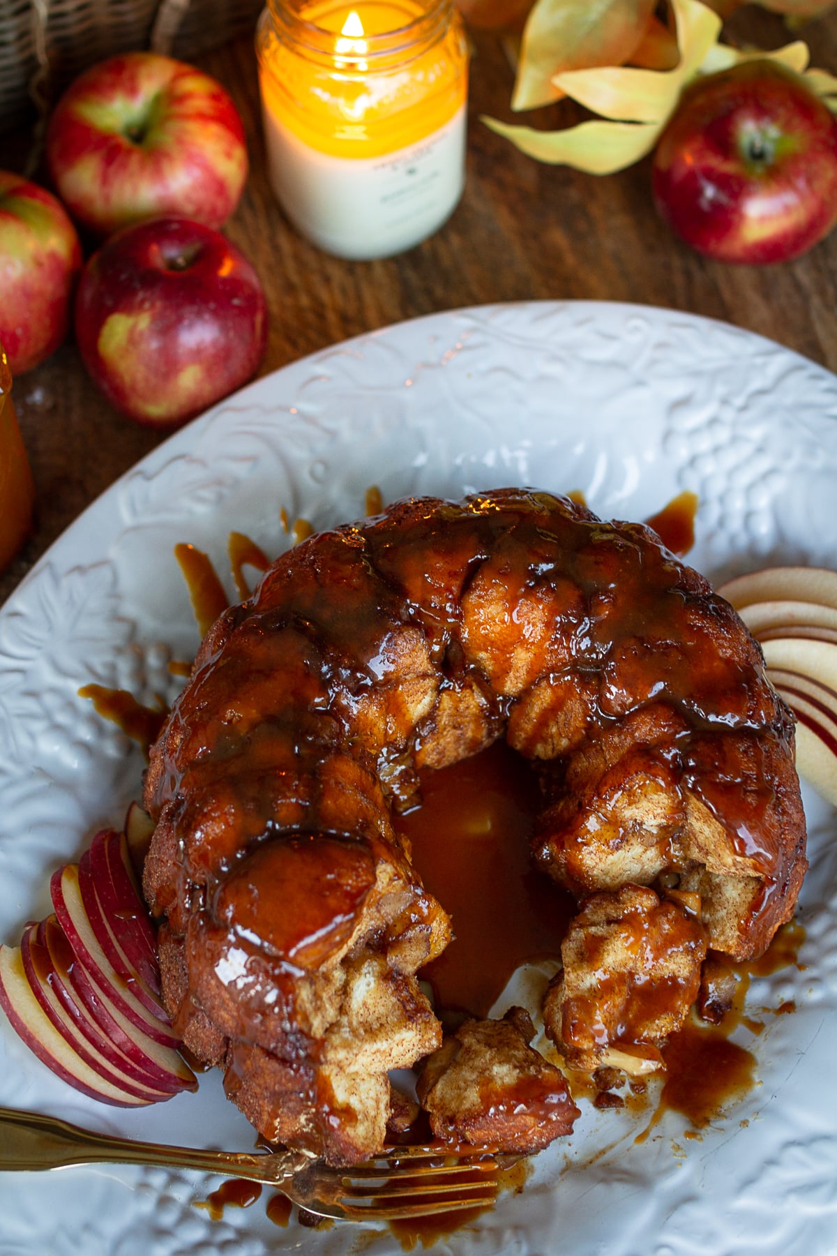 Close-up overhead view of pull-apart caramel apple monkey bread showing sticky cinnamon-sugar dough balls and sliced apples.